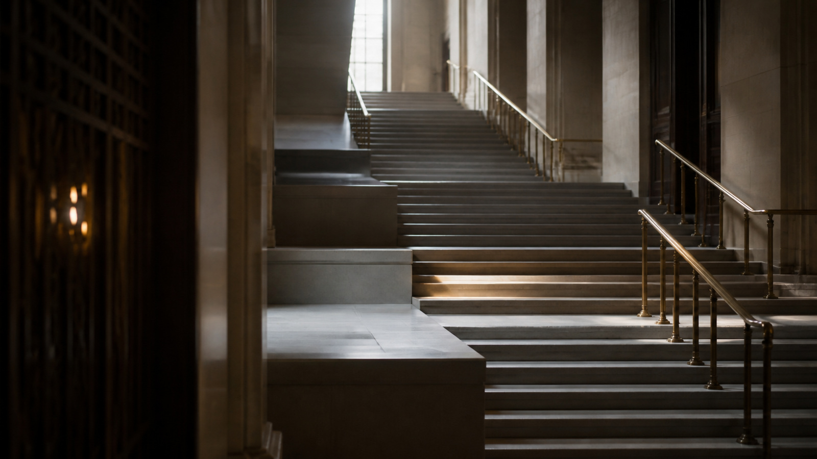 A courthouse staircase rising through three landings in early morning light
