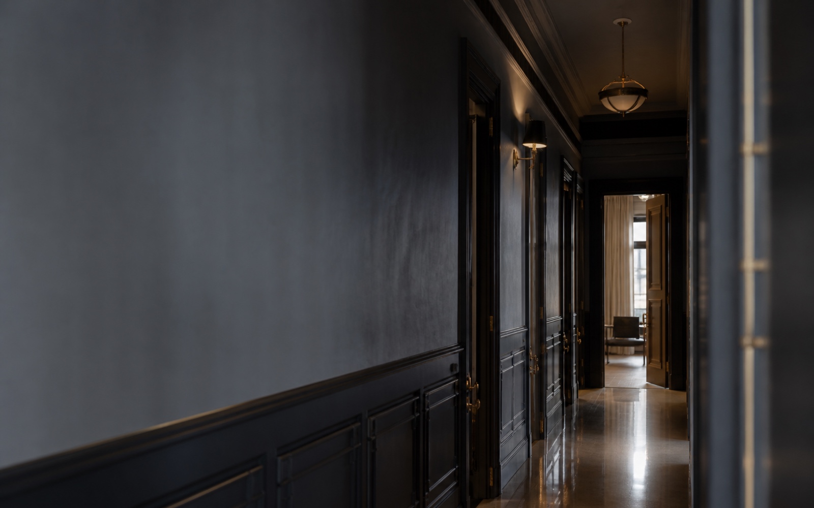 A long empty corridor of courtroom doors, one standing open at the far end