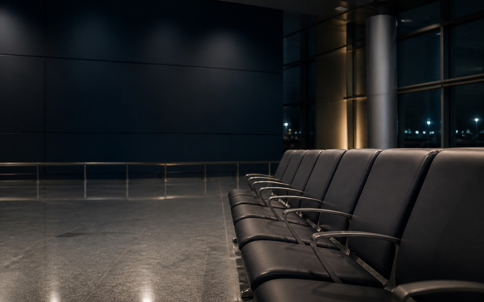A row of empty airport arrivals seats under cold overhead light