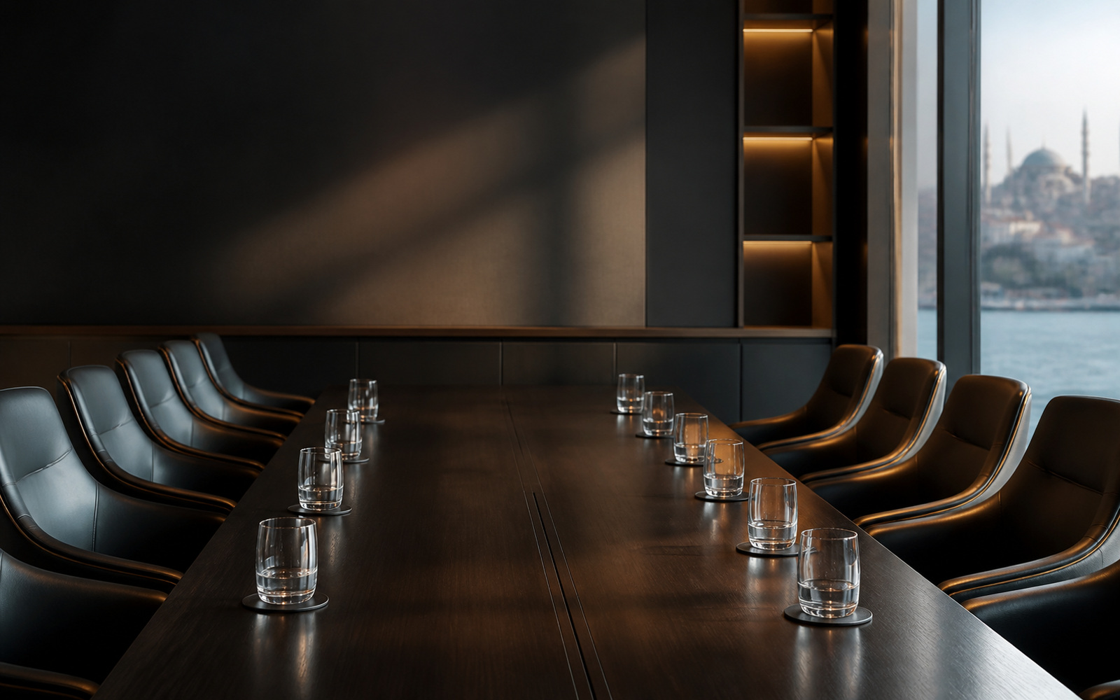 A boardroom table set for two parties, chairs facing across it, no people