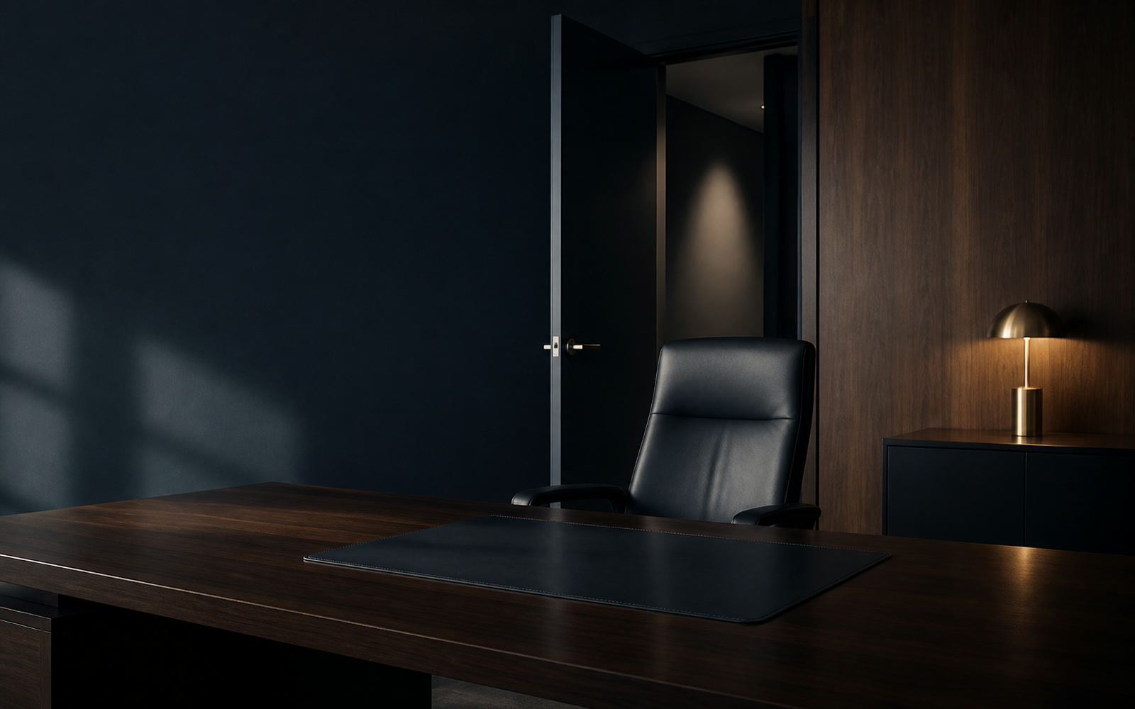 An empty executive chair behind a desk, the office door open onto a dark corridor