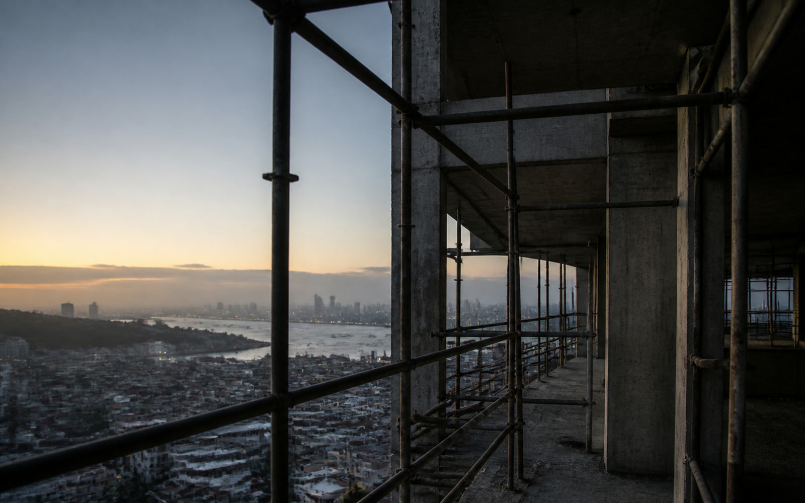 A partly built apartment block seen through scaffolding at first light